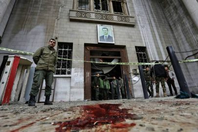 Forças de segurança sírias se reúnem sob um retrato do presidente Bashar Assad no antigo palácio de justiça em Damasco, após um atentado suicida - 15/03/2017 (Louai Beshara/AFP)